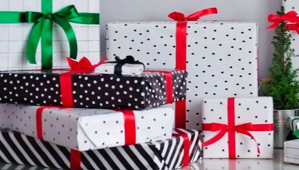 Christmas presents wrapped in black and white patterns with red, black, and green bows..