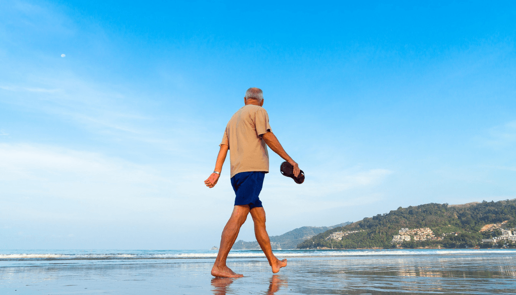 A Senior walking on the beach barefooted