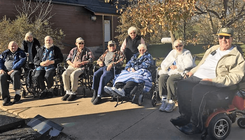 A group of elderly outside sitting in wheelchairs.