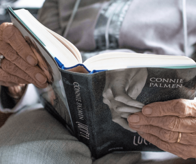 An elderly reading a book, focused on the book and hands.