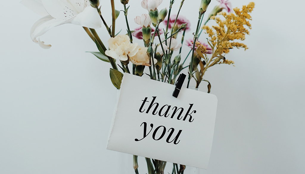 Thank you sign on a vase of flowers.