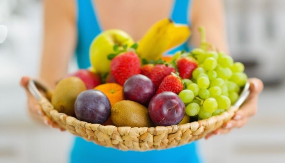 Basket filled with nutrition, grapes, bannanas, apples, plums and strawberrys.