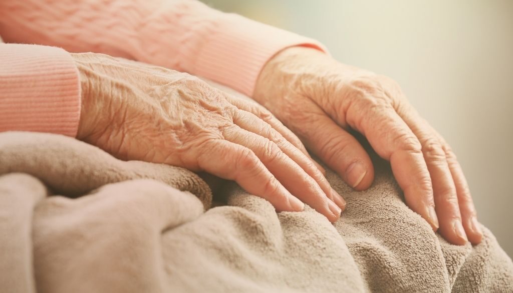 Elderly women skin care hands on lap.