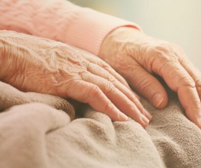 Elderly women skin care hands on lap.