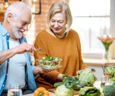 An older man and woman around a table with a variety of healthy food options.