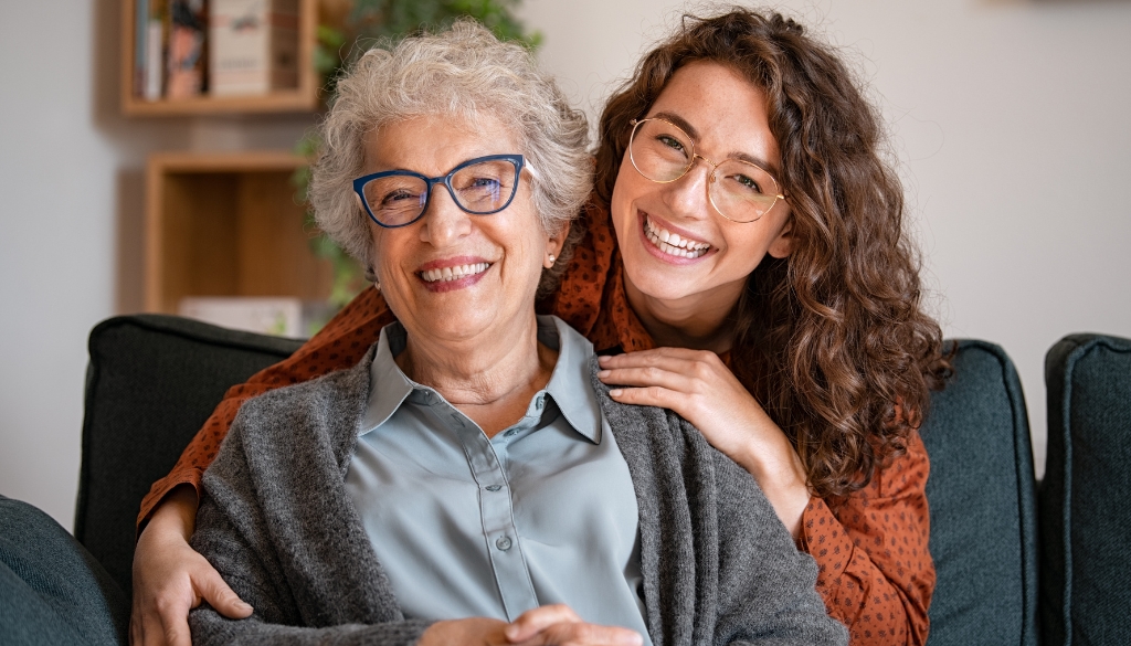 Senior agedd woman being hugged by woman in her 30's. The Neighbors of Dunn County how seniors can maintain relationships in caregiving facilities.