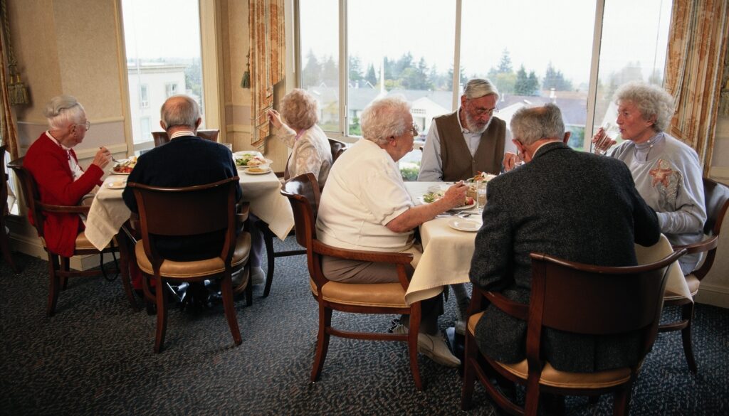 A group of elderly people enjoy a meal.