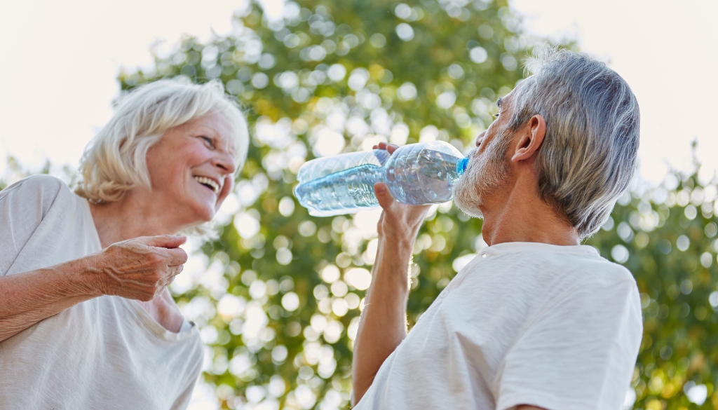 A man drinks water while enjoying a summer day with his wife.