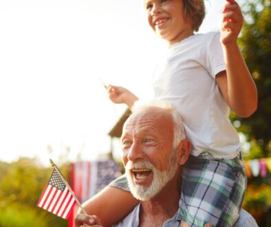 Grandpa carrying grandson on shoulders during a 4th of July celebration.