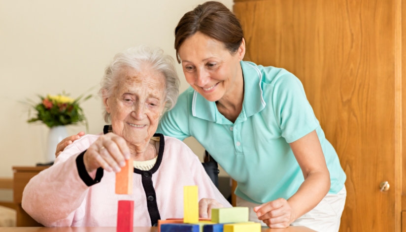 Celebrating Occupational Therapy Month Occupational therapist working with an elderly patient on building blocks.