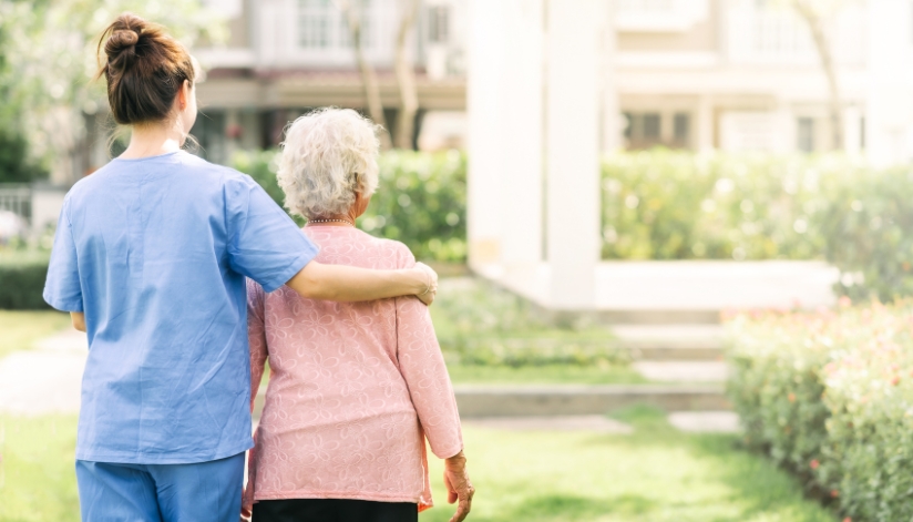 the-neighbors-of-dunn-county-elderly-woman-caregiver-nurse Nurse walking with her arm around an elderly woman at an assisted living facility.