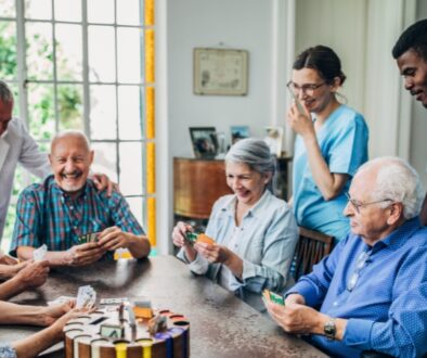 Nursing home residents laughing and smiling while playing a card game.