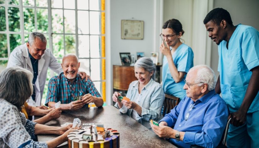 Nursing home residents laughing and smiling while playing a card game.