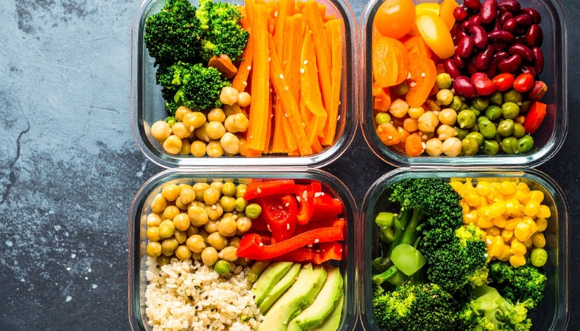Containers filled with broccoli, carrots, garbanzo beans, avocado, and beans.