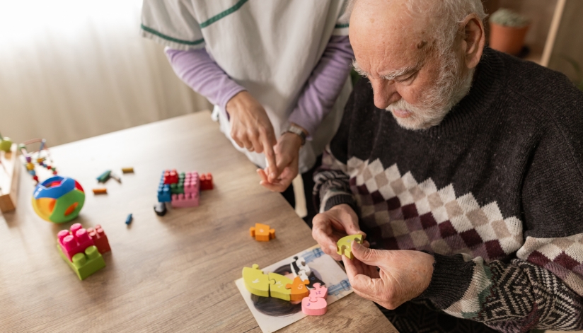 An occupational therapist working with an elderly patient with various puzzle pieces and building blocks.