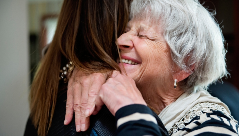 Grandmother hugs her grandaughter and smiles on National Grandparents Day.